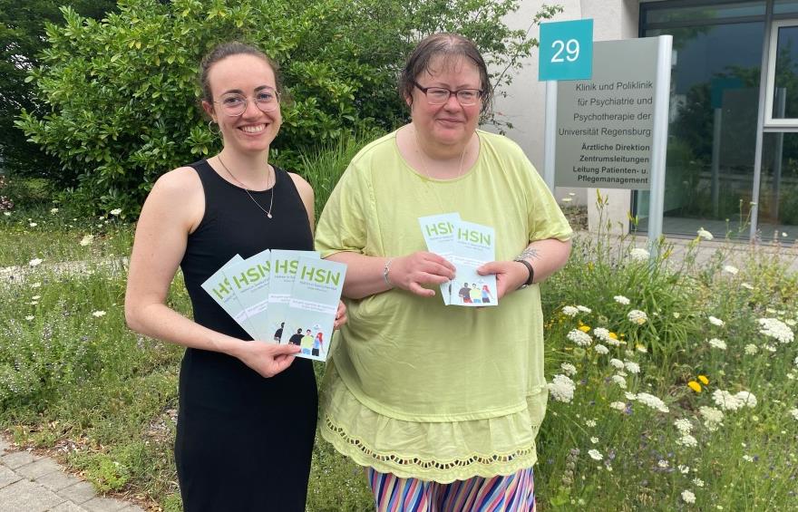 Marina Scheele und Christiane Kerbeck aus dem HSN-Team halten Flyer in der Hand mit dem Titel "Stabile Seitenlage für die Seele"